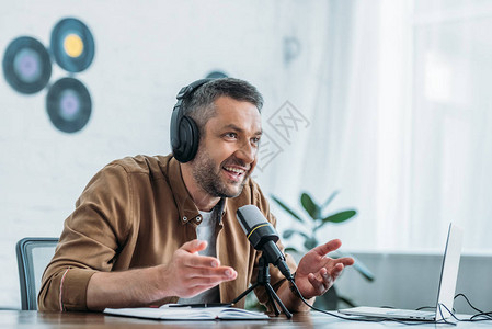 在广播演室用麦克风讲话时使用耳机的有笑声图片