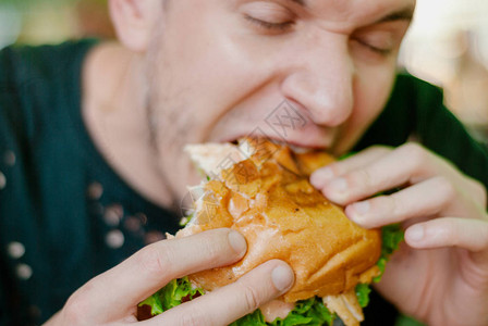 餐馆里的人吃汉堡包他饿了吃着好吃的口图片