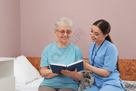 护士与在医院病房的老年妇女一起阅读图片