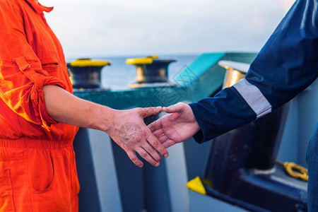 海洋承包商人与船上的工人握手图片