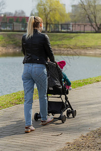 年轻妈带着婴儿在婴儿车里散步图片