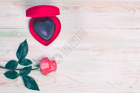 在开放的红色心形盒子里平躺着橙色玫瑰在木制背景图片