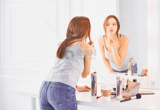 神奇的年轻女人在镜子前化妆图片