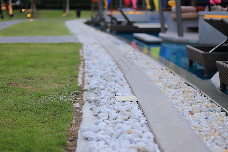 游泳池排水系统格栅覆盖着圆形白河石鹅卵石游泳池建筑细节设计白色鹅卵石与深灰色骨料图片