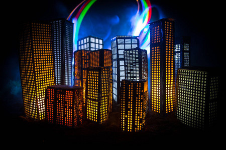 创意艺术品桌装饰与夜间发光的小城市建筑现代摩天大楼明亮的灯光豪华的旅行和旅游理念背景图片