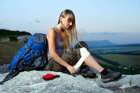 一名女游客在旅途中在山上施用手臂医疗背景图片