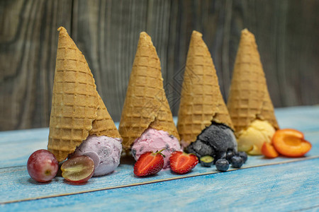 在木制背景上的球中的甜冰淇淋不同口味和新鲜浆果和水果的甜点华夫蛋筒里的冰淇背景图片