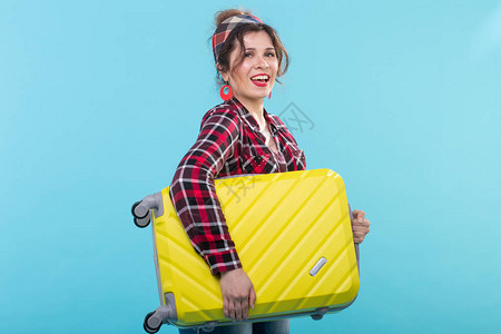 身穿格子衬衫的积极年轻微笑女人拿着一个黄色手提箱图片