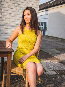 黄色节庆服中平均年龄的亚洲模型坐落于白砖墙户外工业空间和夜间阳光下图片