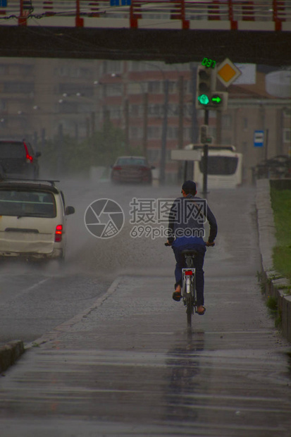 男子在雨中骑自行车在汽图片