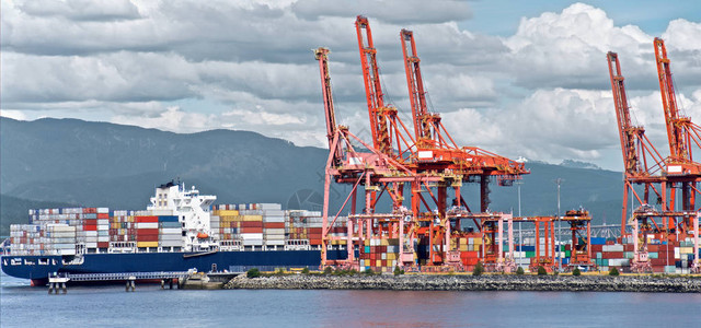加拿大温哥华港集装箱船卸货红色海上起重机和云天背景下多彩集装箱图片