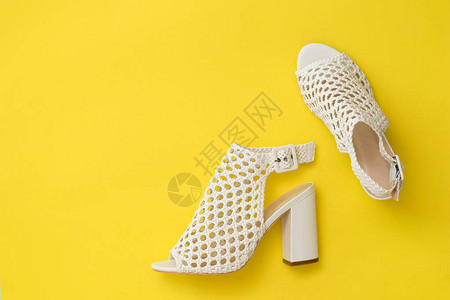 时尚的女鞋由黄色背景的白皮编织而成图片