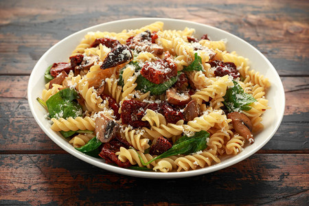 意大利面配晒干的西红柿蘑菇帕尔马干酪和菠菜健康食品图片