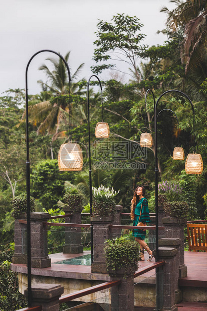 亚洲褐色女人穿着绿衣服在阳台上有着惊人的丛林风景从巴厘图片