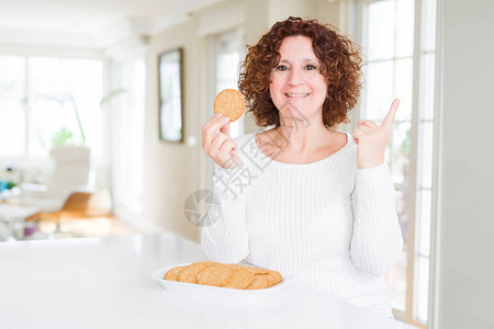 家里吃健康的老妇人在家里吃一整块玉米饼干非常开心地用手和图片