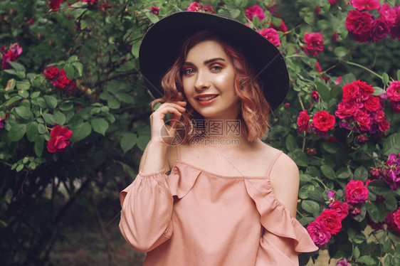 美丽浪漫的年轻女子在粉红色的自然花构成的背景上夏日风情香水化妆品概念一个粉红色头发和黑色帽子的女孩图片