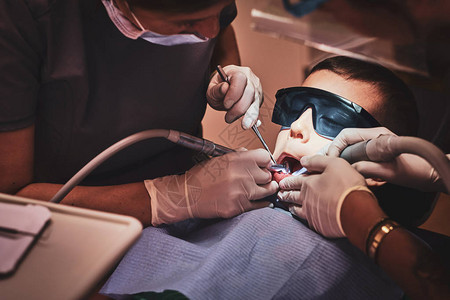 勇敢的小孩在牙科诊所接受有经验的医生的牙科治疗图片