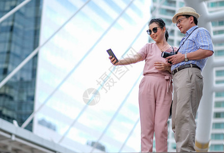 一对亚洲老男人和女人游客正在大城市的大建筑中自拍照片这张照片还包含老年人美图片