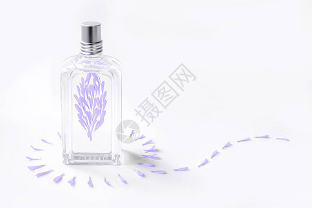白色背景的透明香水瓶配有紫花瓣图片