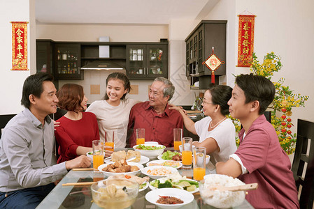 欢乐的亚洲大家庭坐在晚餐桌边庆祝月球新年图片