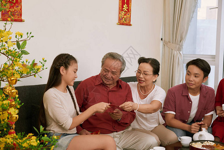 在月新年庆祝活动上向祖父母提供传统资金信封的老年夫妇图片