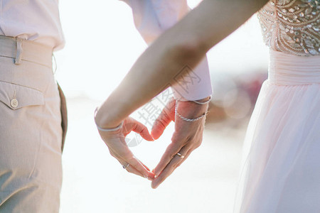 由情人的手或男朋友的女朋友手在自然背景上制作的心形符号恋人用手做心爱情背景图片