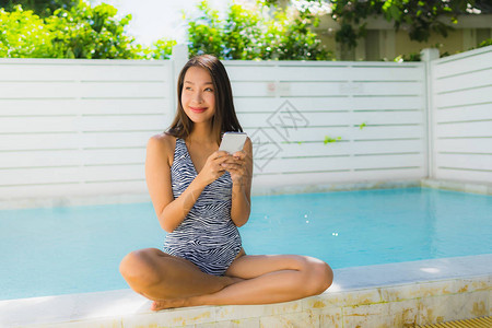 肖像美丽的亚洲年轻女在休闲度假时在游泳池周围用图片