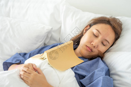 亚洲女孩睡觉时看书人书封面嗜睡导致睡眠充足睡眠的概图片