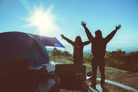 爱人男女亚洲人旅行在假期放松露营在山上站着看日出帐篷图片