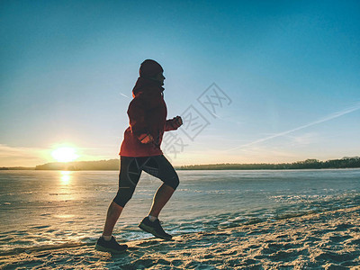 跑步的女人女跑步者穿着温暖的服在寒冷的冬季海湾慢跑健图片