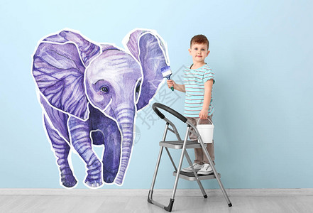 可爱的小男孩在墙上画大象图片