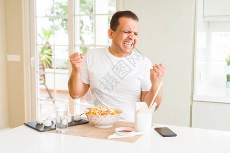 中年男子在家里吃亚洲菜时用筷子图片