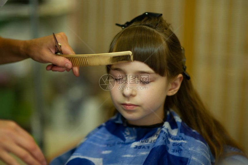 美发师给可爱的小女孩做发型女孩剪掉了刘海工作美发师更改图像改变发型时尚宝贝一系列理发婴图片
