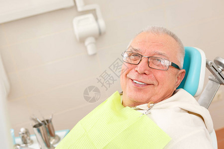 戴眼镜的老人坐在牙医办公室的牙科椅图片