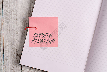 显示增长战略的书写笔记战略的商业概念旨在经典木质背景上的短期笔记本文具中赢得更图片