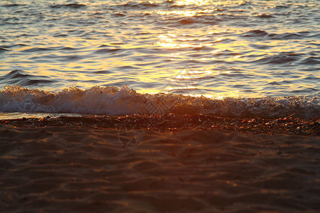 沙滩上的湿海沙与美丽的夕阳相映成趣在日落期间关闭海岸洋上的海沙景观日落海岸日落背景上海滩上图片