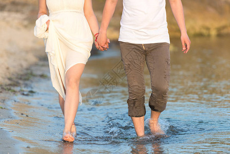 一对夫妇在度假旅行假期的海滩上手牵浪漫地行走将身体和金沙合起来图片