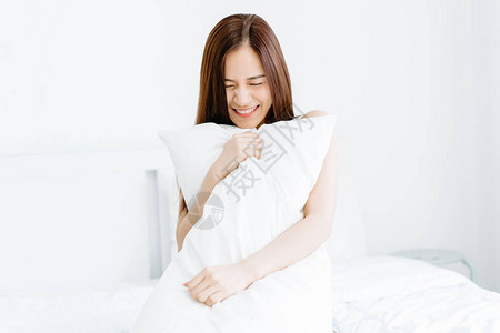 微笑美丽的年轻亚洲女人拿着枕头图片