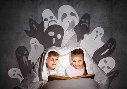 快乐的小孩在床上读魔法童话兄弟姐妹一起躲在毯子下穿着睡衣的小朋友们图片