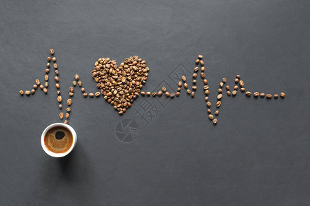 咖啡豆的心电图和黑色背景上的一杯咖啡图片