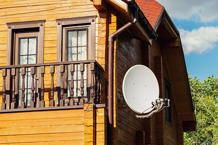 白色抛物线卫星蚂蚁盘挂在现代木制乡村住宅别墅的墙上图片