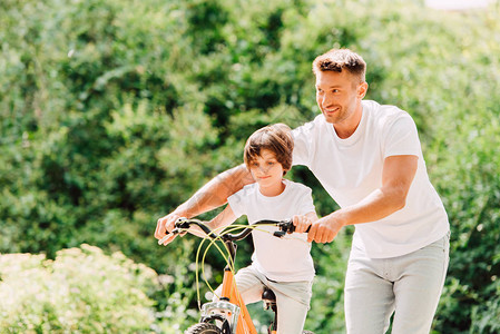 父亲帮助儿子在儿子骑自行车时图片