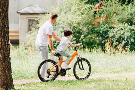 儿子骑自行车和父亲走在孩子旁边图片