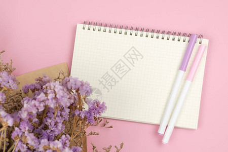 用于粉色粘贴背景的空网格笔记本和紫绿色静态和白色caspia花束图片