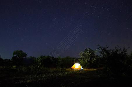 在充满星的美丽夜空下露营帐篷繁星点的夜空在大自然中被照亮的背景图片