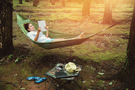 亚洲女自然旅行在假期放松睡在吊床上看书在清迈的茵他侬公园图片