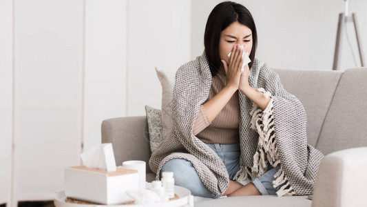 生病的女孩流鼻涕打喷嚏用纸巾擤鼻图片