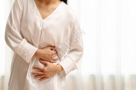 患有腹部疼痛的年轻妇女感到胃痛白种背景图片
