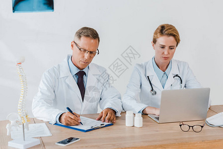 医生在医院使用膝上型笔记本电脑与同事图片