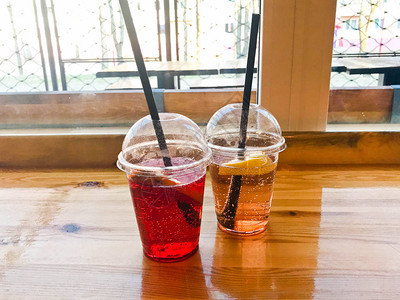 两杯塑料红色和黄色清爽可口的甜覆盆子草莓樱桃橙柠檬水果柠檬水天然与稻图片